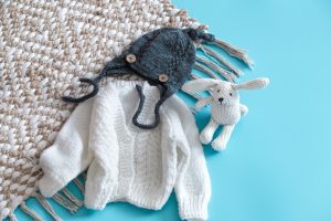 Knitted baby clothes and accessories on a blue background . Bouty Digital Casal Guitarras 2.50m x 2.60m